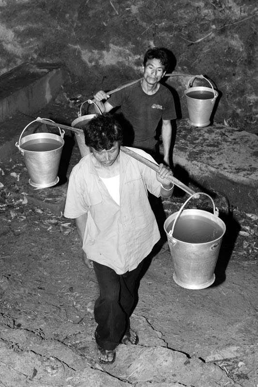 Men and Drinking Water Procurement - Carrying water buckets up the hill to their village at dawn in district Zunheboto, Nagaland
